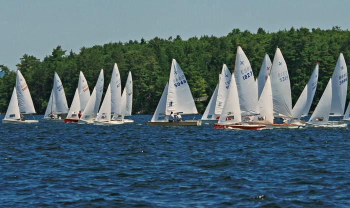 Sailboats racing on a lake with a forest background