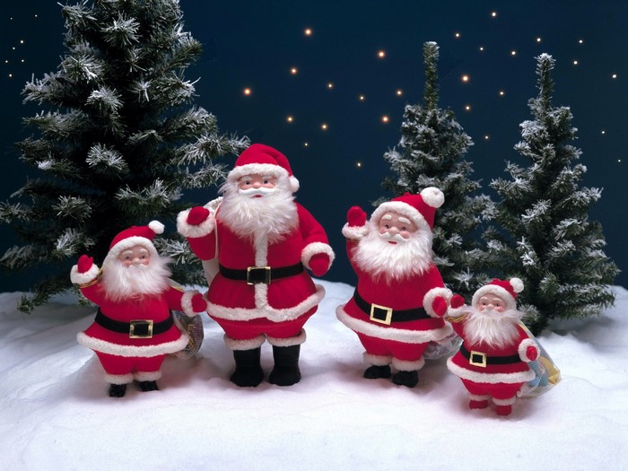 Four Santa Claus figures in a snowy forest setting