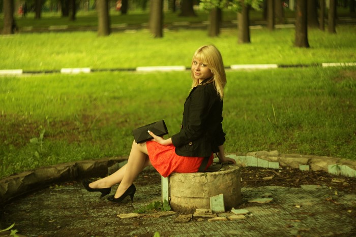 Blonde girl in a red skirt and black jacket with stilettos