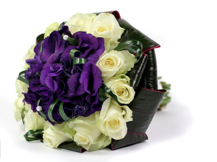 Bouquet of white roses and purple lisianthus with dark green leaves
