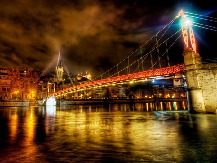 Night view of a lit bridge over a river in Lyon, France