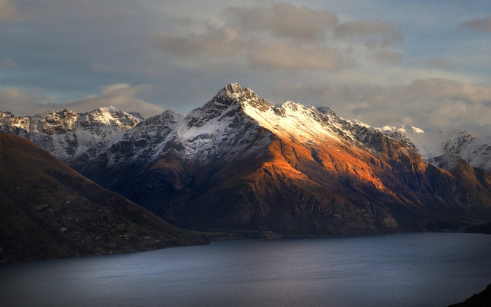 Snow-capped mountains over a lake at sunset