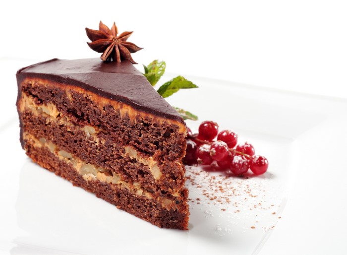 Slice of chocolate cake with star anise and red currants