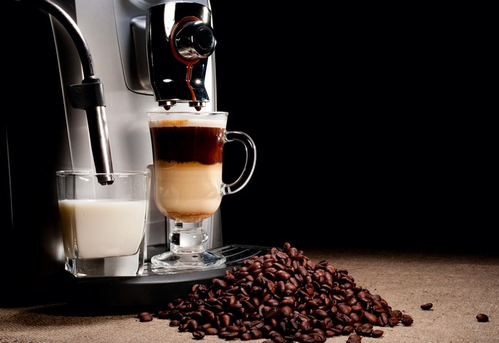 Coffee machine making a layered coffee drink with milk and coffee beans