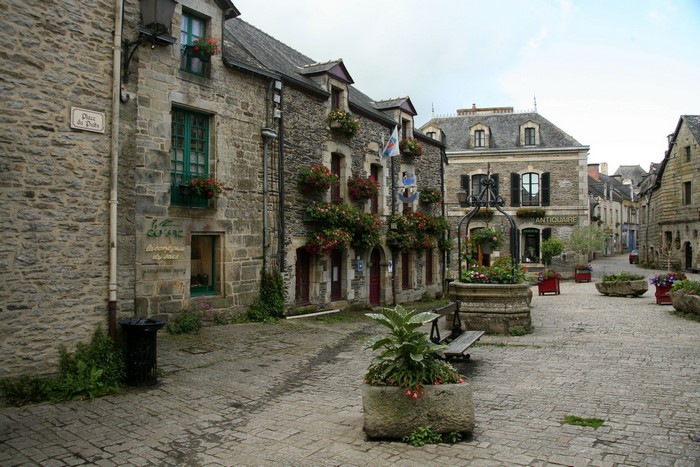 Cobblestone square with stone houses and a well in France