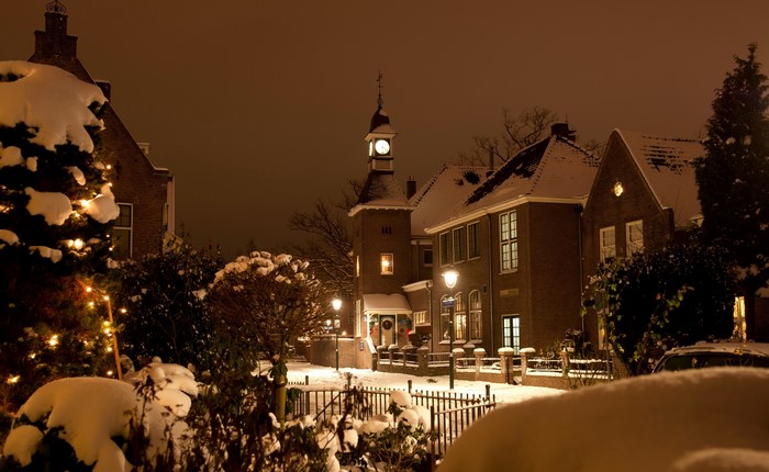 Snowy street at night with illuminated buildings and Christmas tree