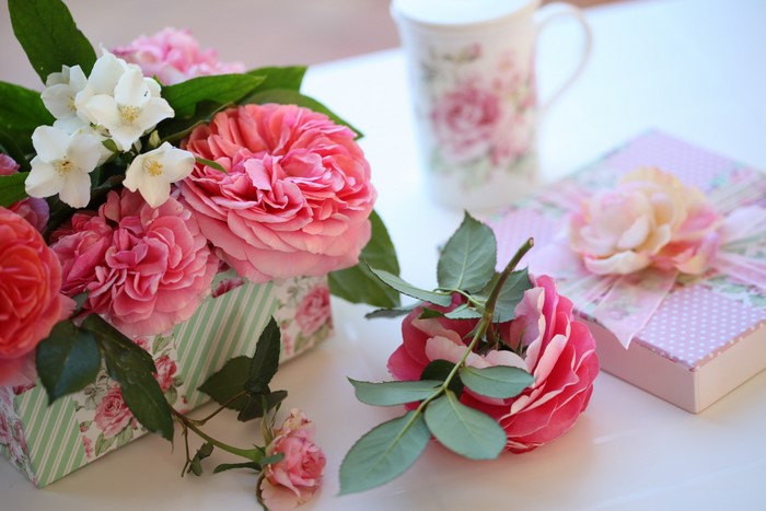 Pink roses and jasmine in a box with gifts and a mug