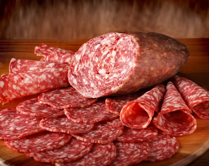 Sliced and whole salami on a wooden board