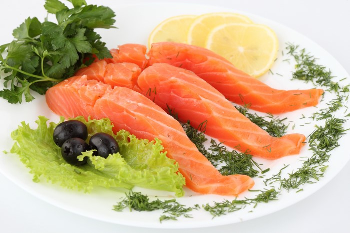 Salmon fillets with lemon, olives, and herbs on a plate