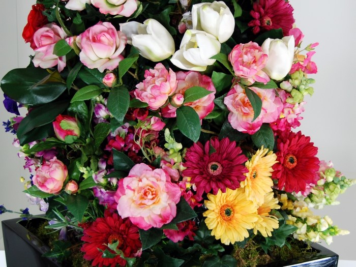 Assortment of artificial flowers in a black vase