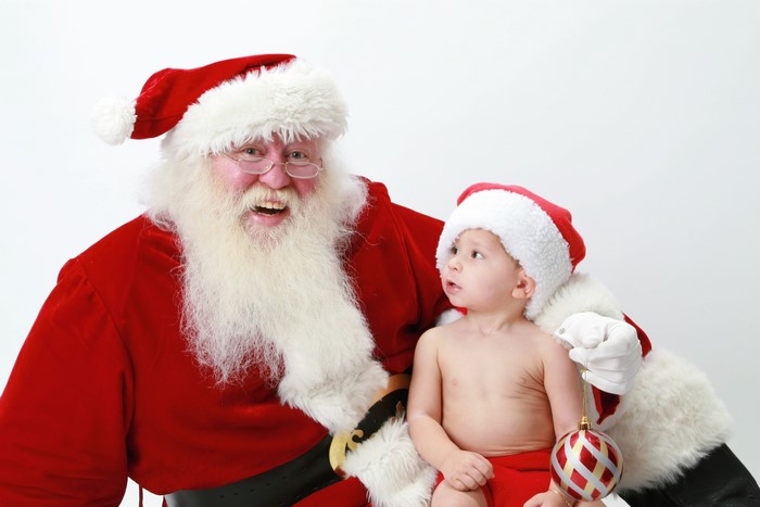 Santa Claus with a baby wearing a Santa hat