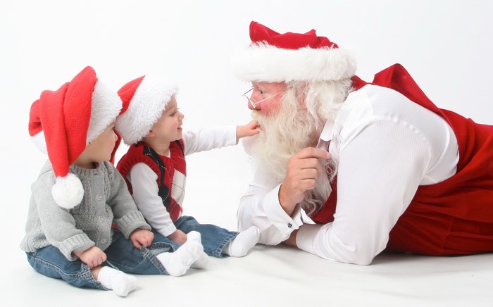 Santa Claus with two babies wearing Christmas hats