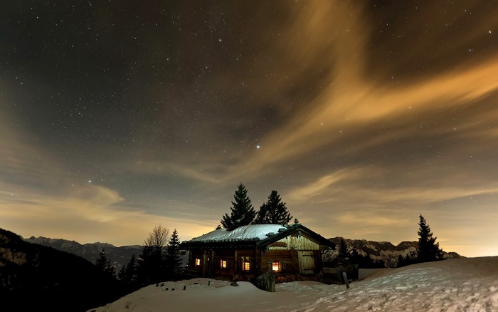 Wooden cabin under starry night sky in winter