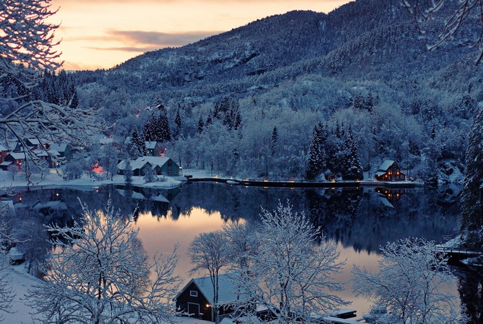 Winter village by a lake with snow-covered mountains