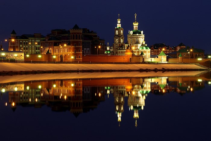 Cityscape with illuminated buildings and river reflection at night