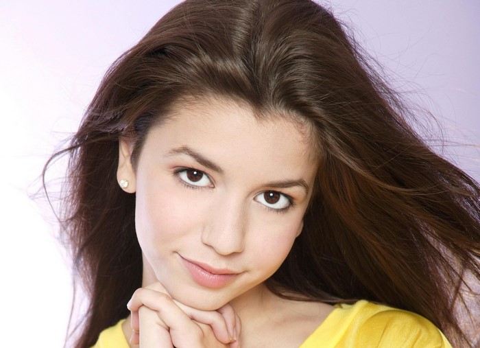 Masiela Lusha with brown hair and a yellow shirt