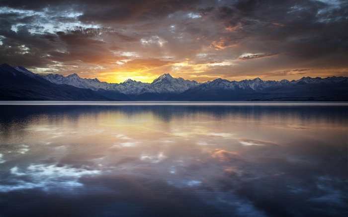 Sunset over snow-capped mountains reflected in a lake