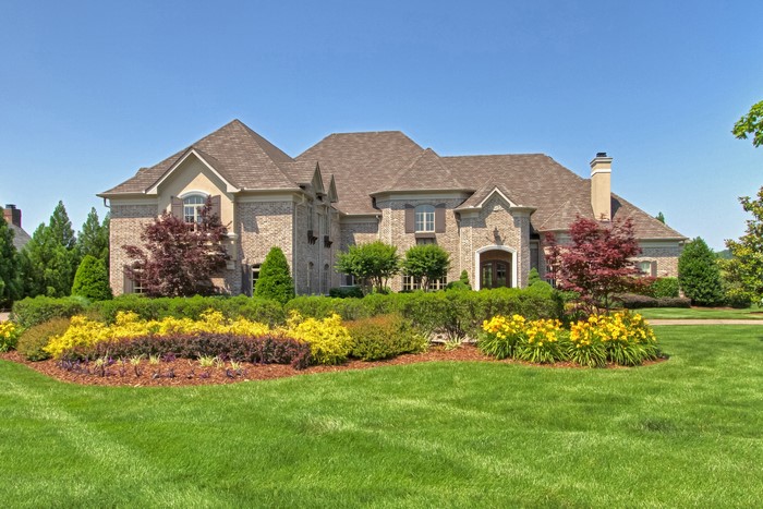 Large brick mansion with manicured gardens and lawn