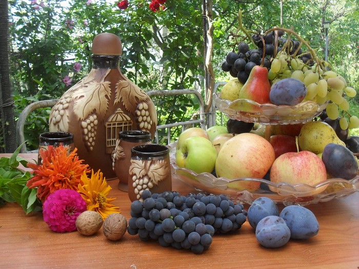 Still life with fruit, grapes, apples, plums, and a decorative bottle
