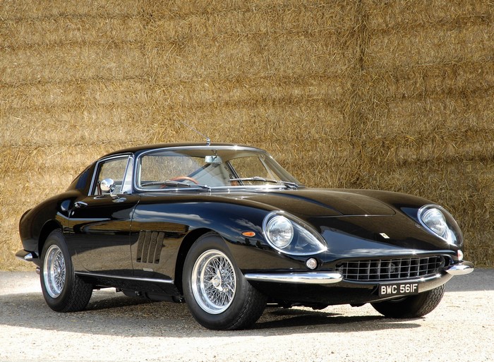 Black Ferrari 275 GTB/4 parked in front of hay bales