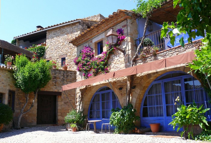 Stone building with blue arched windows and flowers