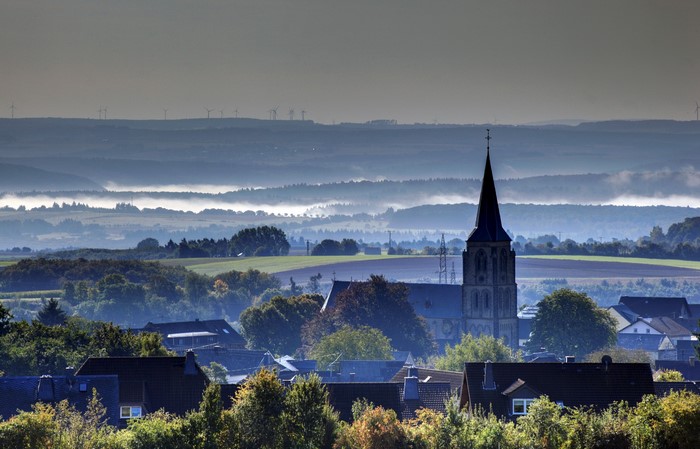 Village with church and wind turbines in Germany