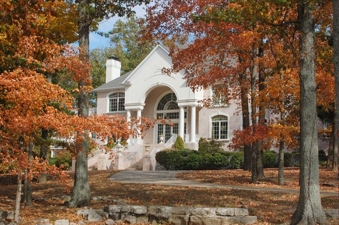 A large white house surrounded by autumn trees
