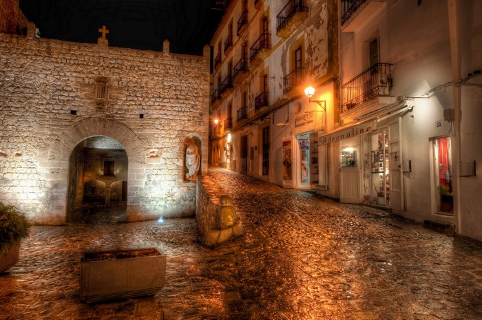 Night street in Spain with stone gate and shops