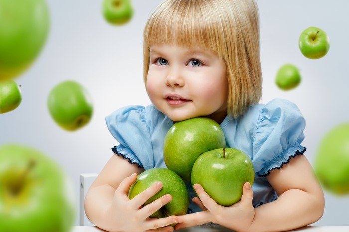 Little girl holding green apples
