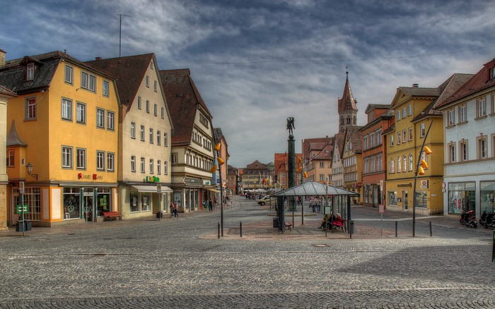 Cobblestone square with colorful buildings and a monument
