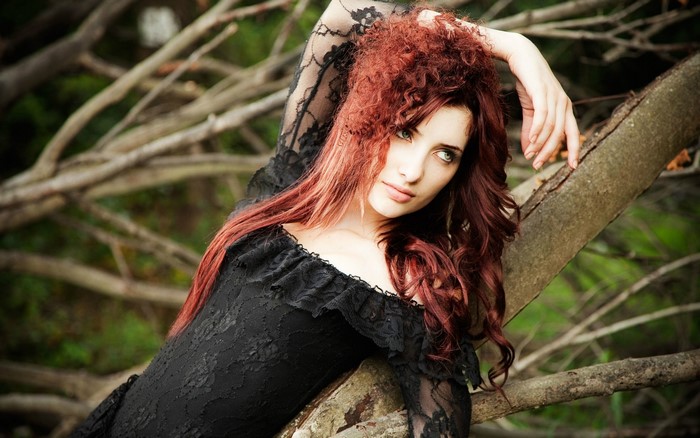Redhead woman in black lace dress on branches