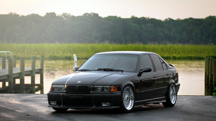 Black BMW sedan parked by a dock