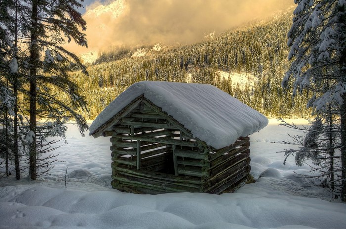 Snow-covered log cabin in a winter forest