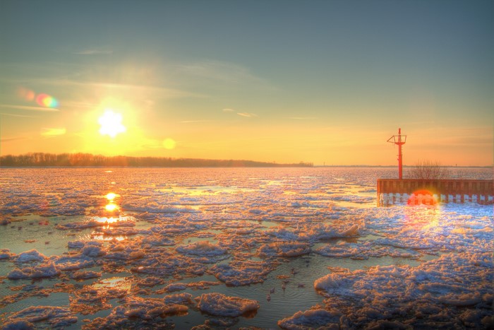 Sunrise over icy river with lighthouse