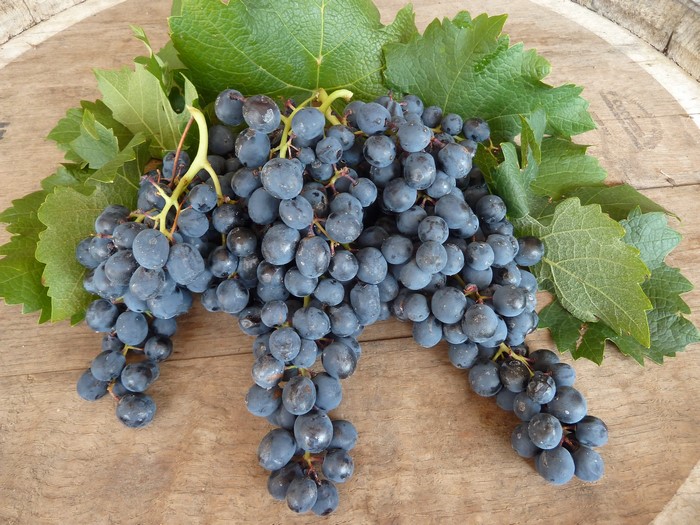 Grapes with leaves on a wooden surface