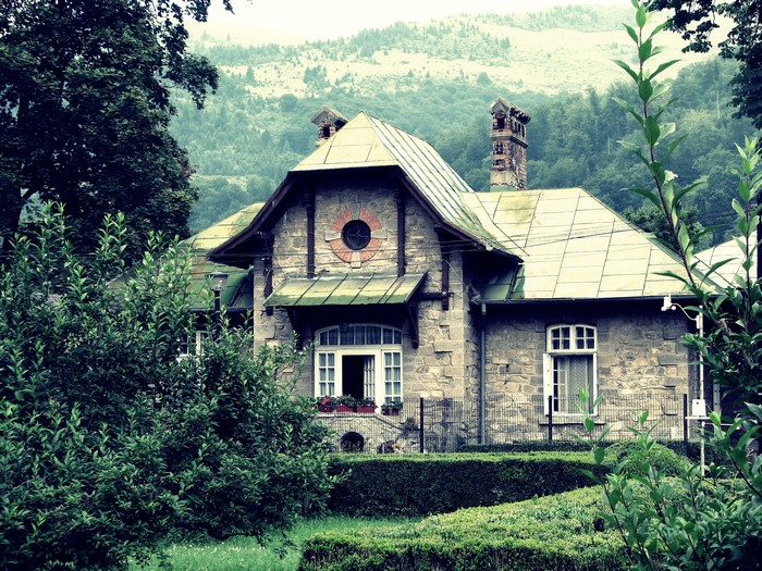 Stone mansion with green roofs and trees