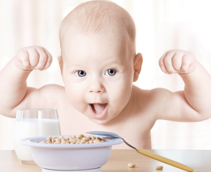 Baby flexing muscles with cereal and milk