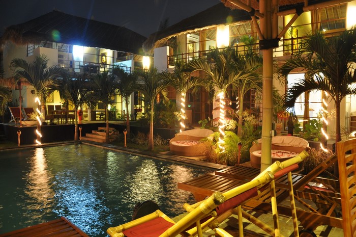 Resort pool area at night with palm trees and lounge chairs