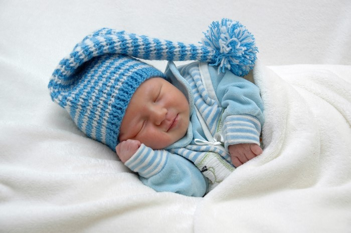 Newborn baby sleeping in a blue striped hat