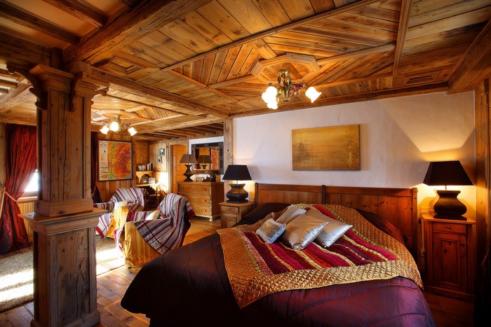 Wooden bedroom with bed, lamps, and chandelier
