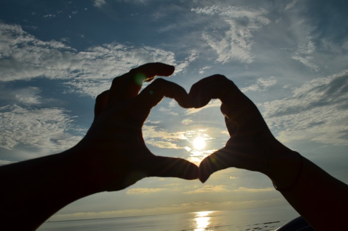 Hands forming a heart shape at sunset