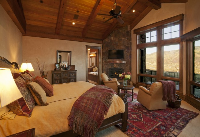 Luxury bedroom with stone fireplace and mountain view