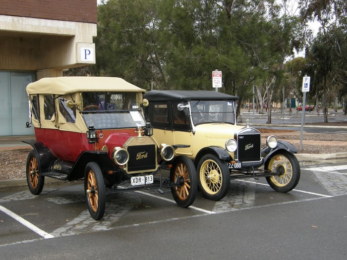 Two vintage Ford cars parked in a lot