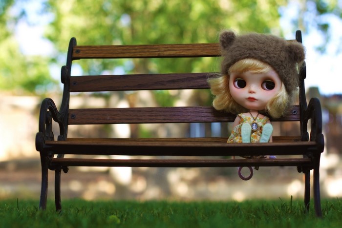Doll wearing a bear hat on a park bench