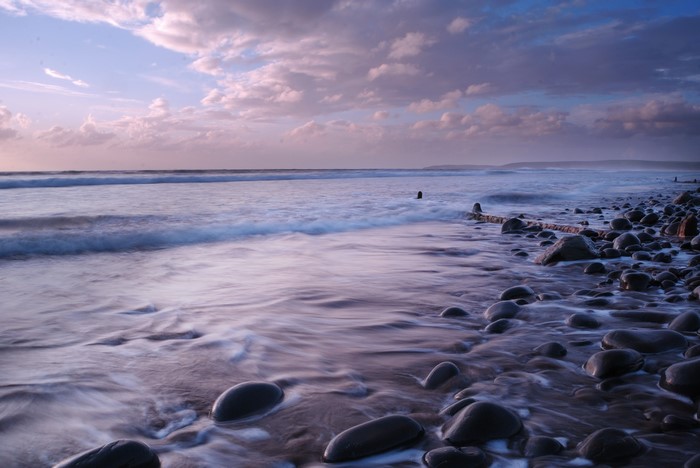 Ocean waves crashing on a rocky beach at sunset