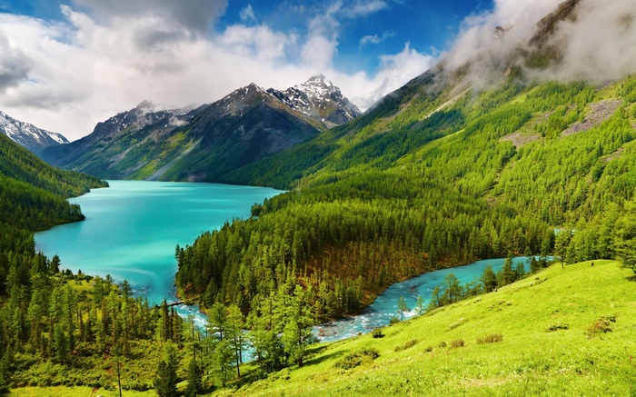 Turquoise lake surrounded by green forest and snow-capped mountains