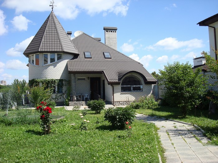 A brick house with a conical tower and a garden