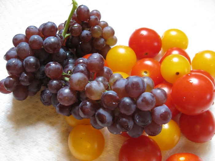 Grapes and cherry tomatoes on a white surface