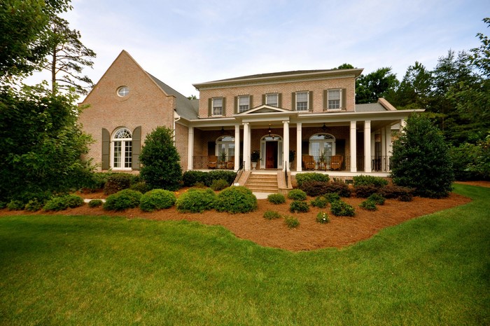 Brick house with a large porch and manicured lawn