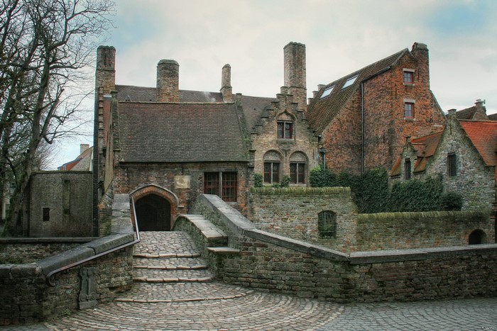 Stone bridge leading to brick buildings in Belgium